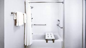 A white bathroom with a bathtub, a shower, and a small wooden stool.
