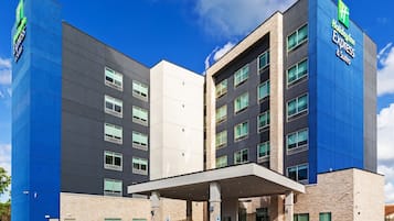 A Holiday Inn Express hotel with a modern design, featuring a prominent blue and beige color scheme, multiple floors, and a covered entrance area.