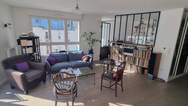 Un salon spacieux comprenant un canapé, des fauteuils, une table basse et une bibliothèque.