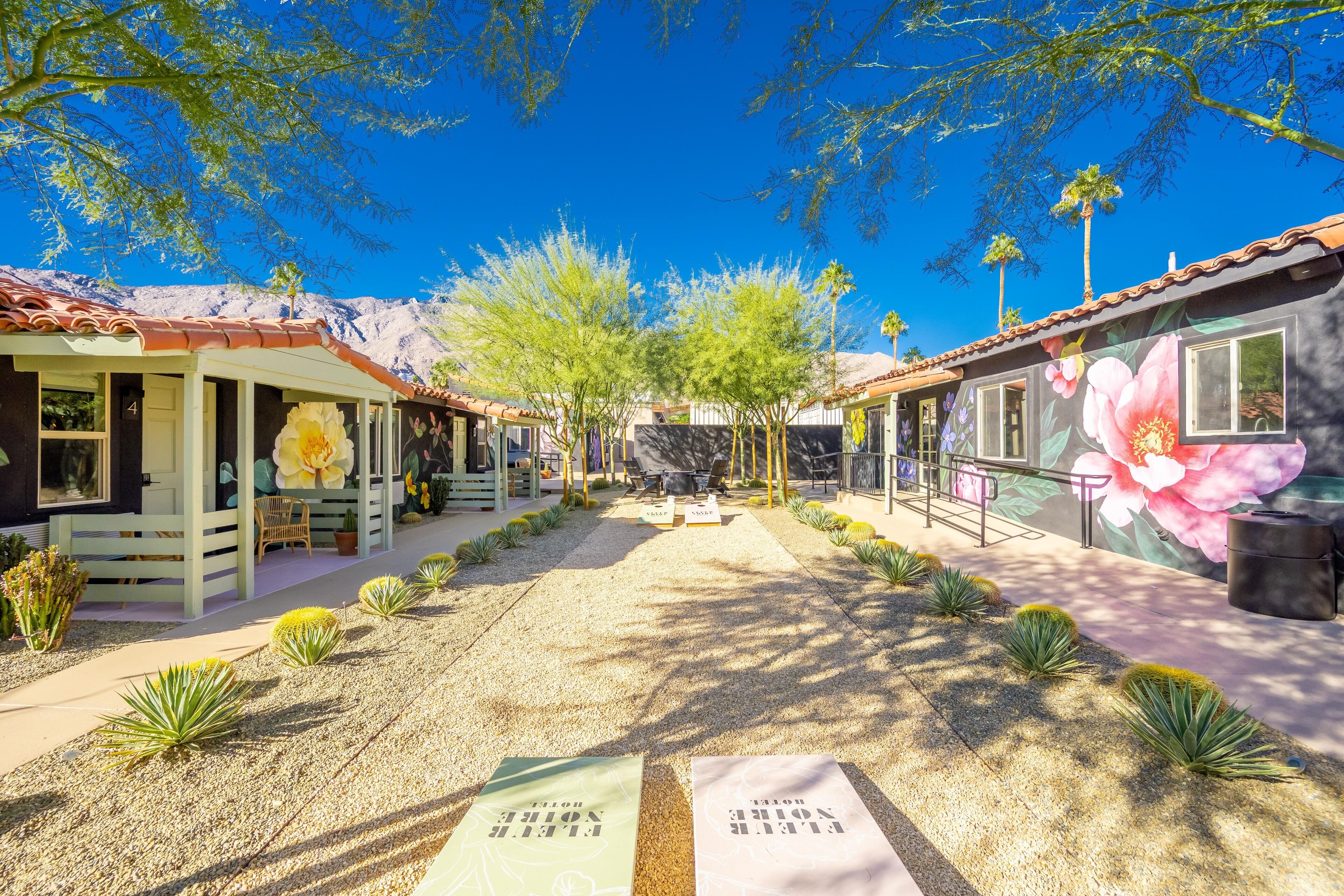 A courtyard with a gravel path, potted plants, and a mural on the building.