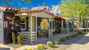 A building with a tiled roof, a large flower mural, and a cactus garden. - Fleur Noire Hotel - 21 and Over (Palm Springs)