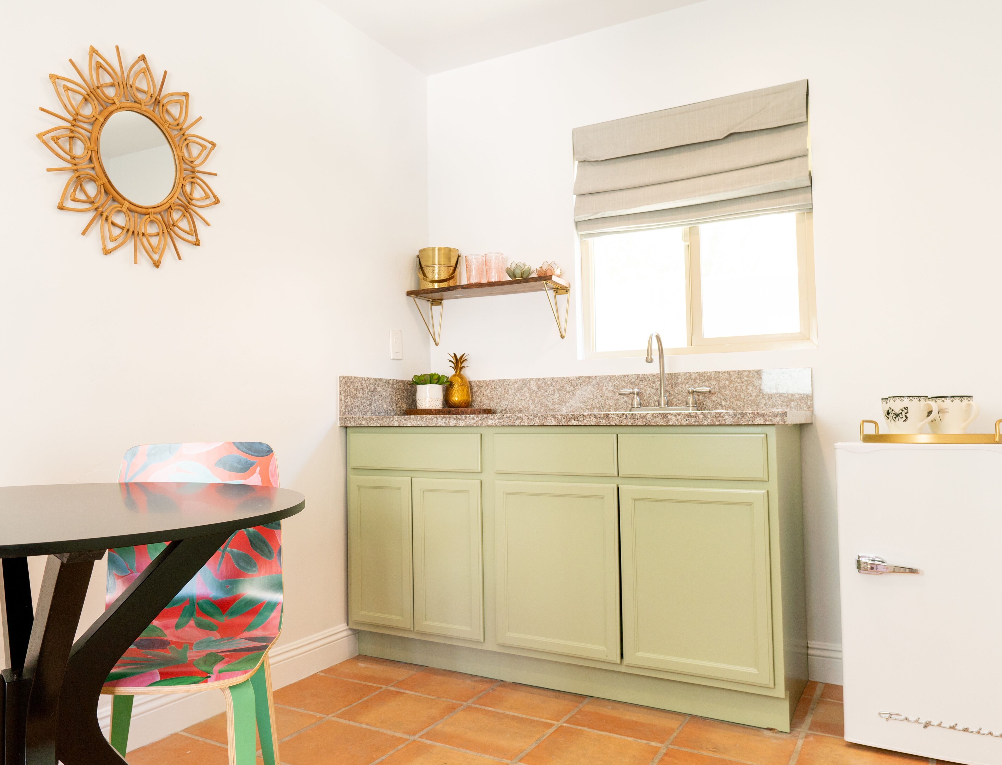 A compact kitchen with a green cabinet, a white refrigerator, a sink, and a window with a blind.