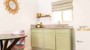 A compact kitchen with a green cabinet, a white refrigerator, a sink, and a window with a blind.