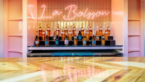 A bar area with a neon sign reading "La Boisson" and a display of various bottles. - Fleur Noire Hotel - 21 and Over (Palm Springs)