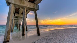 A pier extending into the ocean with a sunset in the background.