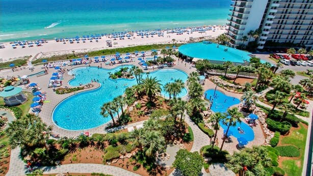 A resort with multiple swimming pools, a beach, and a large hotel building.