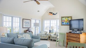 A living room with a sofa, armchairs, a TV, a wooden cabinet, and a ceiling fan. - Lauren Lee: Private Pool, Hot Tub, Golf Discounts (Nags Head)