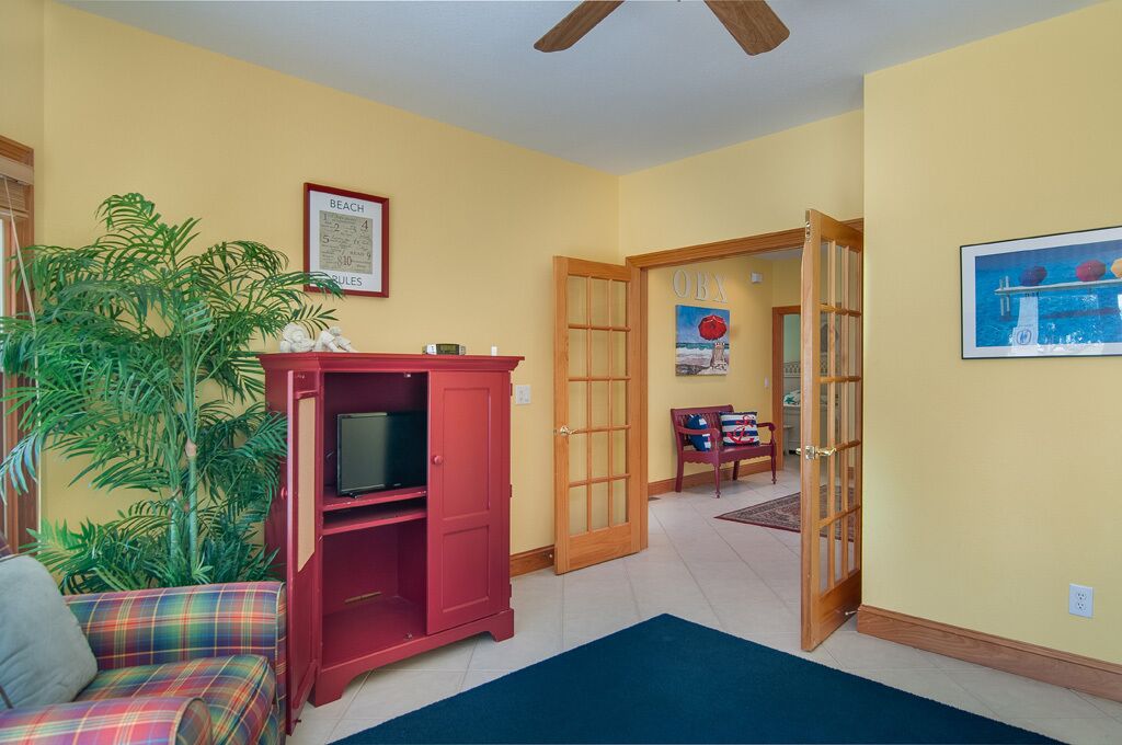 A living room with a red entertainment unit, a large plant, and a framed picture on the wall.