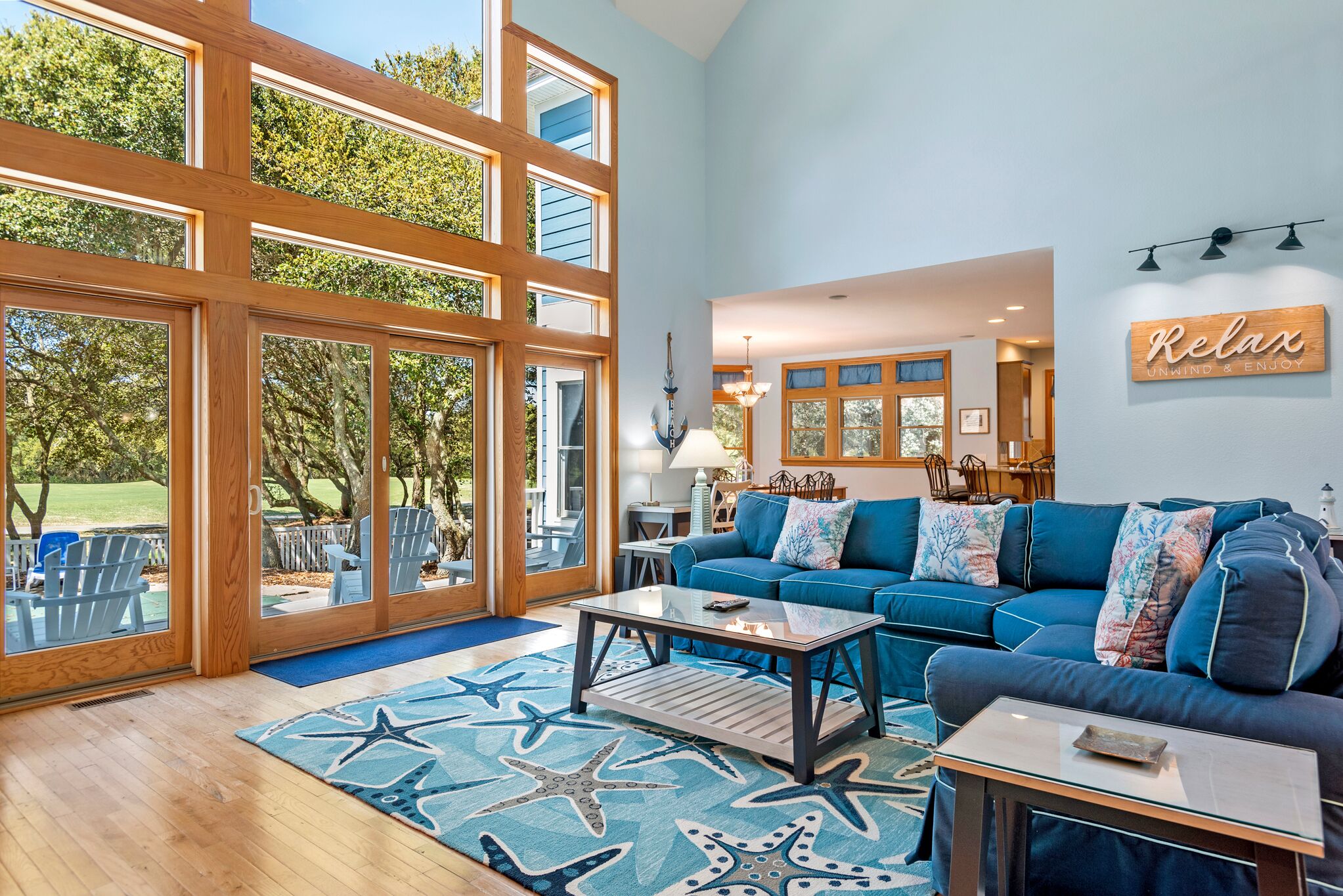 A spacious living room with a large window, a blue sofa, and a star-patterned rug.