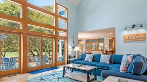 Ein geräumiges Wohnzimmer mit großem Fenster, einem blauen Sofa und einem Teppich mit Sternenmuster.