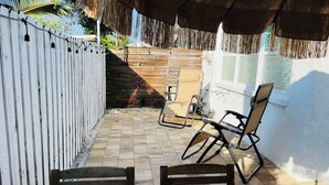Une terrasse couverte avec des meubles en bois, une clôture blanche et une fenêtre.