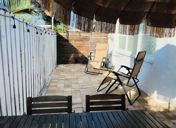 Une terrasse couverte avec des meubles en bois, une clôture blanche et une fenêtre.