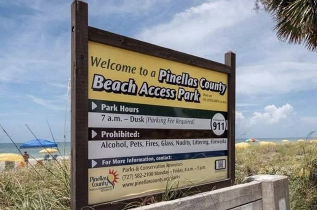 A sign for Pinellas County Beach Access Park with park hours, prohibited items, and contact information.