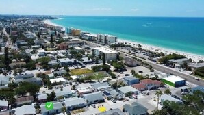 Vue aérienne d’une ville côtière avec une plage, des bâtiments et une route.