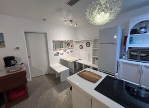 Une cuisine compacte dotée d’un plan de travail blanc, d’une cuisinière encastrée et d’un réfrigérateur.