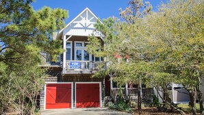 A two-story building with a white exterior and a red garage door. - Reminiscent: Oceanside, Private Pool, Spa (Nags Head)