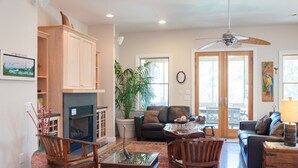 A spacious living room with a fireplace, comfortable seating, and a large window providing natural light. - Reminiscent: Oceanside, Private Pool, Spa (Nags Head)