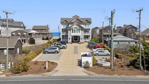 Um hotel à beira-mar, com entrada central, estacionamento e vista para o mar.