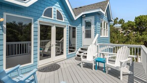 A blue house with a deck, white chairs, and a blue table. - Treasured Dreams: Private pool, Short Drive to Beach, Great Community Amenities! (Corolla)