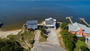 A coastal property with a large house, a smaller building, and a dock extending into the water. - All Decked Out: Soundfront | Rooftop Decks (Nags Head)