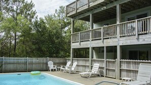 Un bâtiment à deux étages doté d’un espace piscine comprenant des chaises longues et un flotteur.