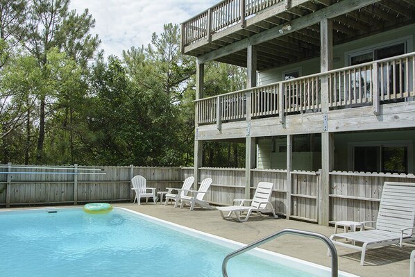 A two-story building with a pool area, including lounge chairs and a floating ring. - Almost Heaven: Awesome Views, Private Poo & Hot Tub, Pet-friendly (Corolla)