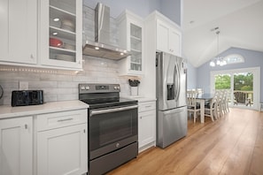 A modern kitchen with white cabinetry, a stainless steel refrigerator, an oven, and a toaster.