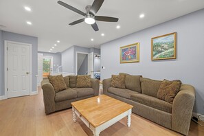 A living room with two sofas, a coffee table, a ceiling fan, and two framed pictures on the wall. - Almost Heaven: Awesome Views, Private Poo & Hot Tub, Pet-friendly (Corolla)