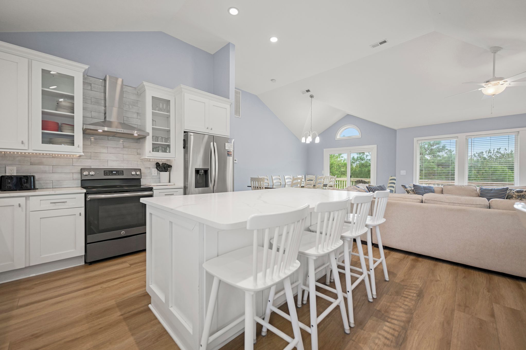 A modern kitchen with white cabinetry, a central island with bar stools, a built-in oven, and a refrigerator.