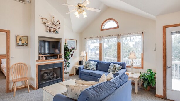 A living room with a fireplace, a blue sofa, a television, and a ceiling fan. - A Dolphin's Cove: Rec Room w/ Pool Table, Private Pool & Spa, Dogs OK! (Corolla)
