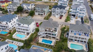 A residential area with multiple houses, each featuring a swimming pool and a front porch. - Craba-Cabana: Surf, Sand, and a Private Pool; Community Pool and Tennis Court (Corolla)