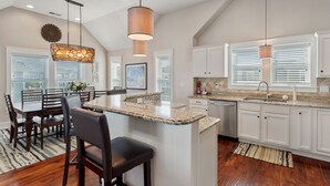 A modern kitchen with white cabinetry, granite countertops, and a central island. - A Ruff Life: Saltwater Pool, Hot Tub, 500 ft. to the Beach, Dog-friendly (Corolla)