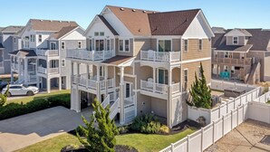 A multi-story residential building with balconies, a covered patio, and a driveway. - A Ruff Life: Saltwater Pool, Hot Tub, 500 ft. to the Beach, Dog-friendly (Corolla)
