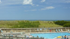 Un pontile in legno con piscina, poltrona relax e vista sull'oceano.