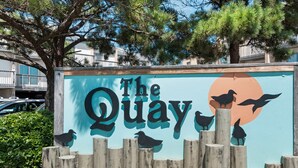 Segnaletica per 'The Quay', con una recinzione in legno e sagome di uccelli.