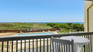 Eine Holzterrasse mit Pool, Liegestühlen und Blick auf den Ozean.