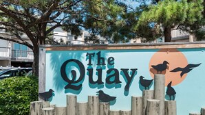 Ein Schild mit der Aufschrift "The Quay" und Silhouetten von Vögeln und einer Sonne.
