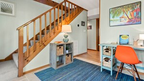 Un escalier avec des rampes en bois, un tapis à rayures bleues et un bureau avec une chaise.