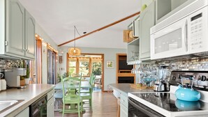Une cuisine moderne avec des meubles en bois, un îlot central et un coin repas agrémenté de chaises vertes.