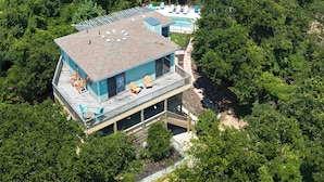Une maison moderne dotée d’une terrasse sur le toit, d’une piscine et entourée d’une vaste forêt.