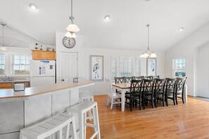 A spacious kitchen with a central island, wooden dining table, and chairs. - Summer Rental: Semi-oceanfront, Pool, Rec Room (Nags Head)