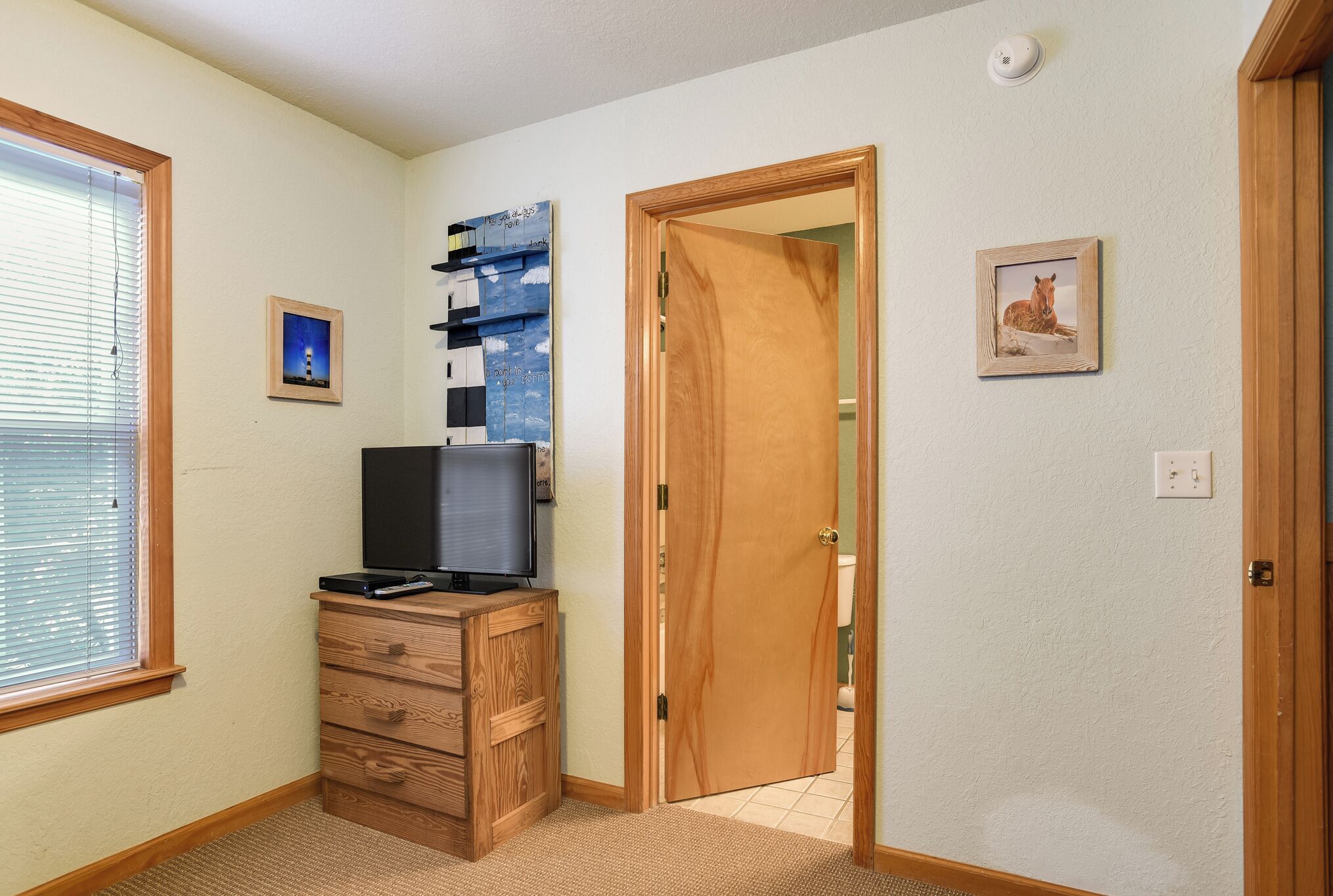 A room with a wooden dresser, a television, and a door leading to another room.
