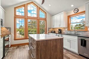 Enjoy cooking in this kitchen with a large island and ample workspace, featuring white cabinetry and a window with a view.