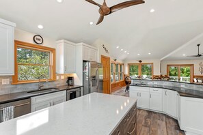 Enjoy cooking in this well-lit kitchen with a large island, sink, and stainless steel refrigerator.