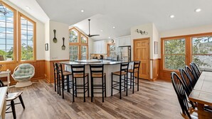 A spacious kitchen with a large island, wooden flooring, and large windows. - Joyful Sound: Soundside 5-bedroom, Private Pool & Spa, Elevator and Dog-friendly (Corolla)