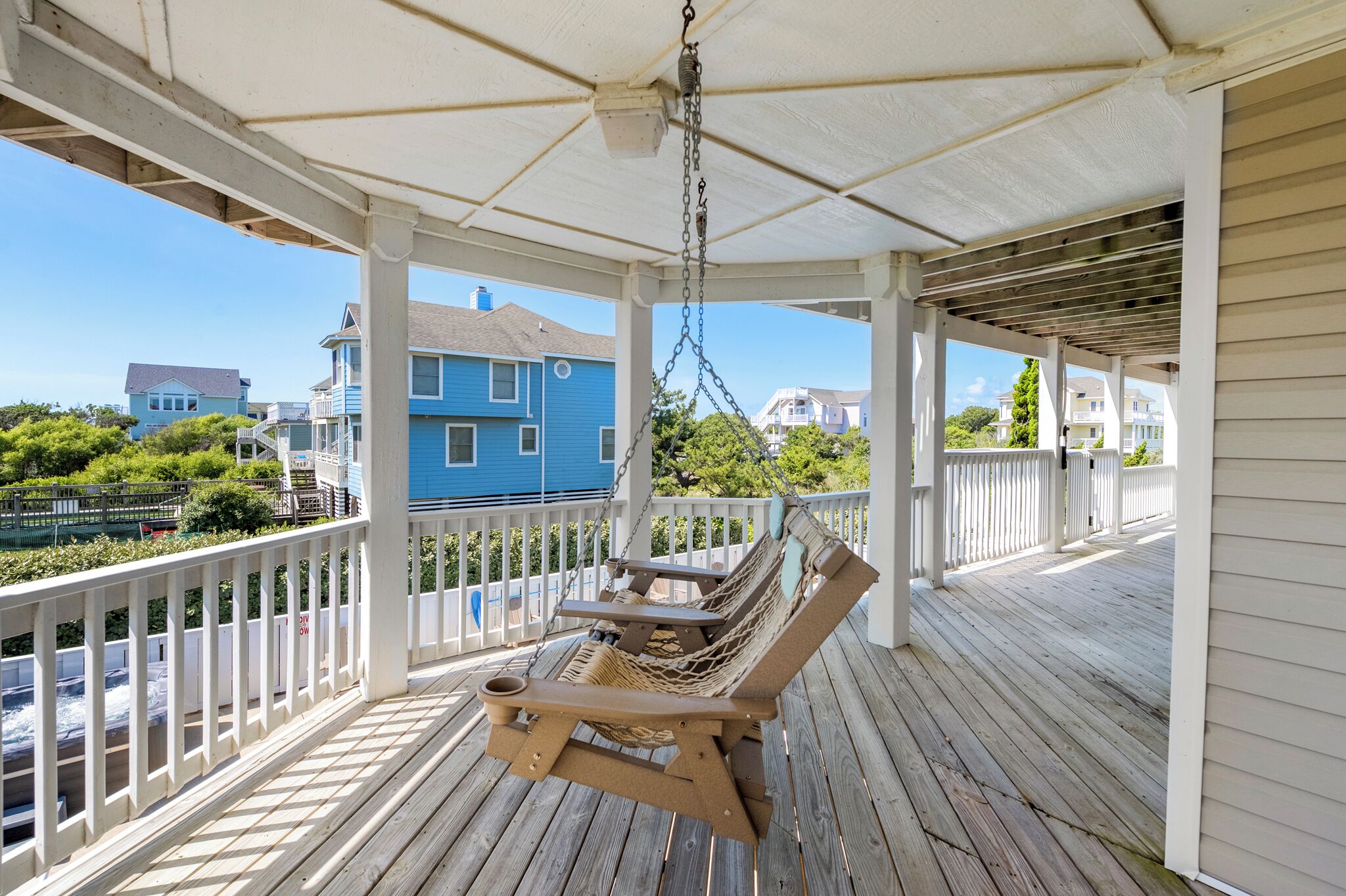 A wooden porch with a hammock chair and a hanging light fixture.