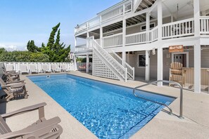 A swimming pool with a white deck and lounge chairs, a staircase leading to a second level, and a sign indicating a restaurant. - E=M(Sea)2: Private Pool & Hot Tub, Rooftop Deck w/ Ocean View, Pet-friendly (Corolla)
