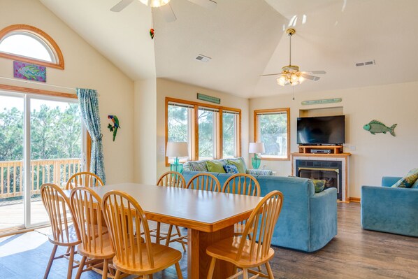 A spacious living area with a dining table and chairs, a blue sofa, and a fireplace.