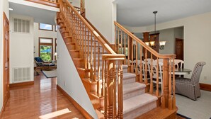 A spacious staircase with wooden railings and carpeted steps leading to an upper floor. - Sea-Esta: Private Pool | Hot Tub | Foosball Table (Corolla)