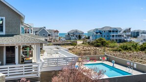 A residential area with a swimming pool, a deck, and houses with balconies overlooking the beach. - The Wheelhouse: Pool and Hot Tub | 500ft. to Beach (Corolla)